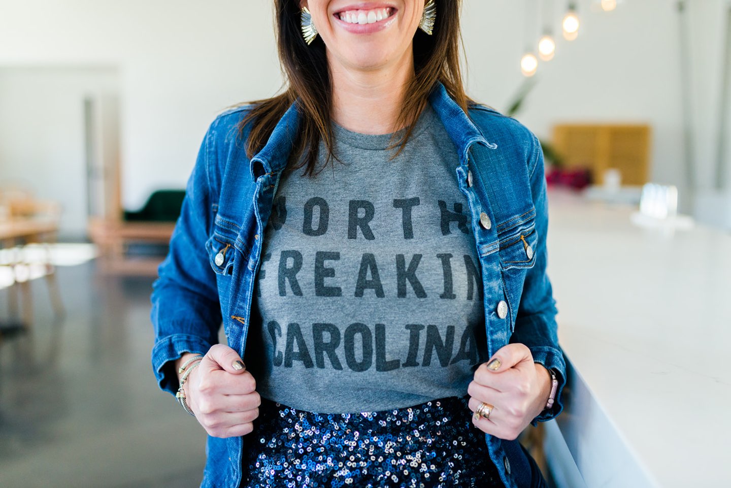 Top US lifestyle blog, I’m Fixin’ To features her birthday reflections as she turns 32:image of a woman wearing an Edge of Urge t-shirt, Eliza J sequin skirt, Vince Cameo booties, Quay sunglasses, Mignonne Gavin statement earrings, a leather cross body handbag and a J Crew Factory denim jacket