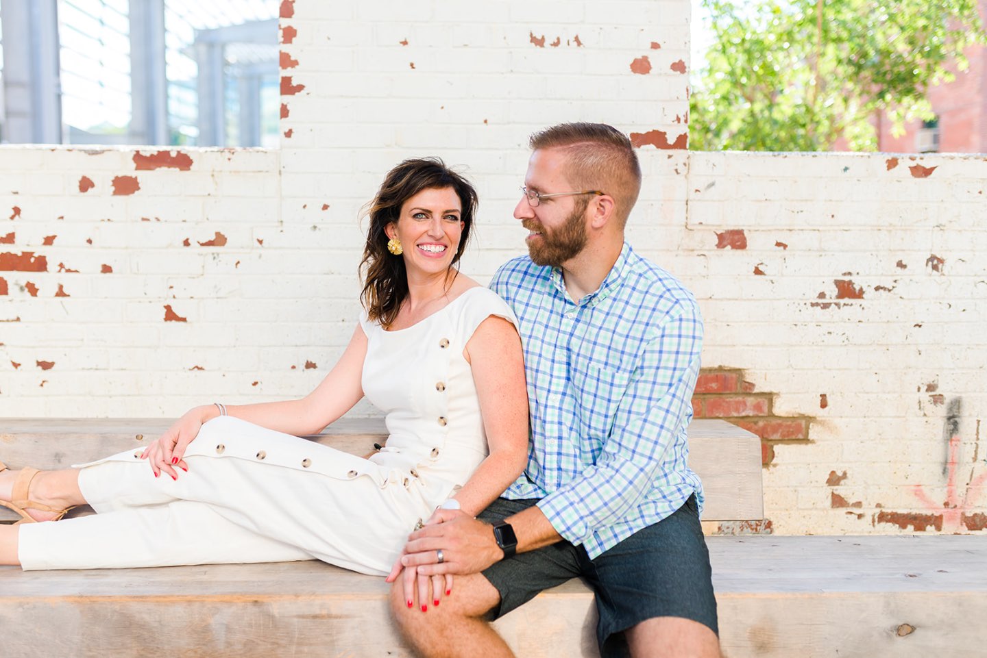 Celebrating 5 Years of Marriage: Lessons Learned - I'm Fixin' To - @mbg0112 | Celebrating 5 Years of Marriage: Lessons Learned - I'm Fixin' To - @mbg0112 | Celebrating 5 Years of Marriage: Lessons Learned by popular North Caroline Life and Style blog, I'm Fixin' To: image of husband and wife sitting next to each other outside and holding hands. Woman is wearing a Gal Meets Glam jumpsuit, Nordstrom Ebba Sandal by ONO, Ray-Ban Original Aviator Polarized Sunglasses, and Hunter Blake Earrings.