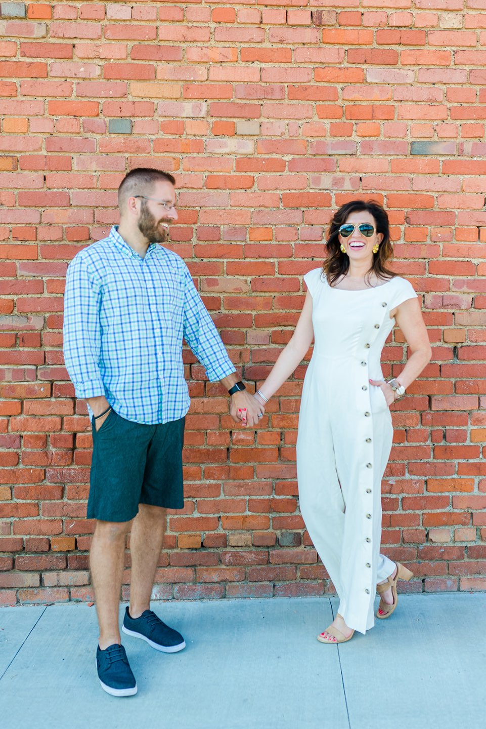 Celebrating 5 Years of Marriage: Lessons Learned - I'm Fixin' To - @mbg0112 | Celebrating 5 Years of Marriage: Lessons Learned by popular North Caroline Life and Style blog, I'm Fixin' To: image of husband and wife standing next to each other outside and holding hands. Woman is wearing a Gal Meets Glam jumpsuit, Nordstrom Ebba Sandal by ONO, Ray-Ban Original Aviator Polarized Sunglasses, and Hunter Blake Earrings.