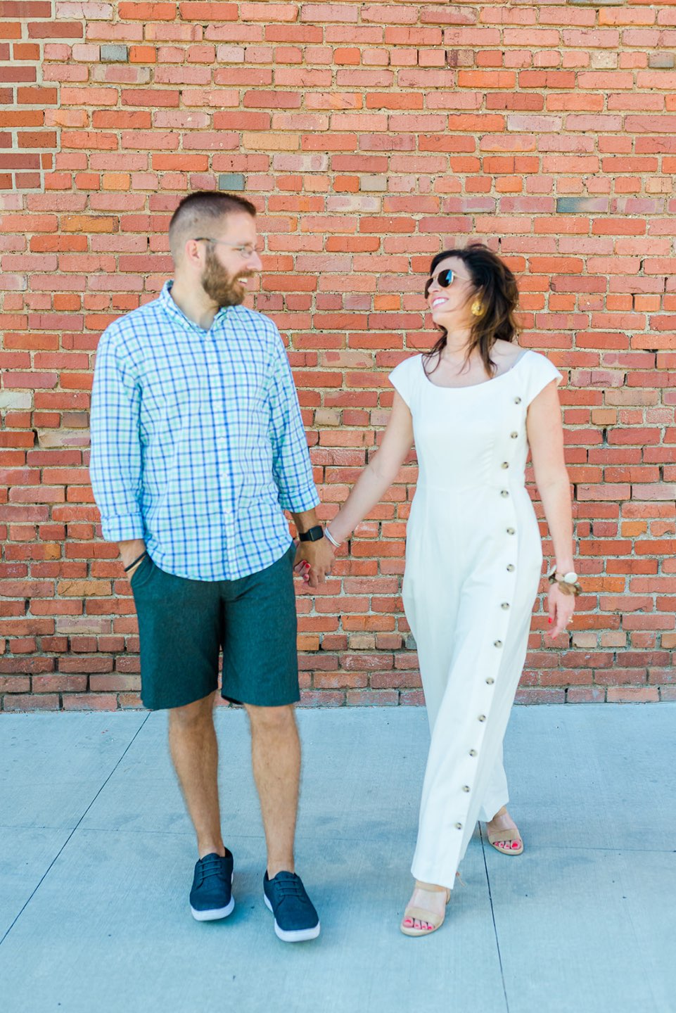 Celebrating 5 Years of Marriage: Lessons Learned - I'm Fixin' To - @mbg0112 | Celebrating 5 Years of Marriage: Lessons Learned - I'm Fixin' To - @mbg0112 | Celebrating 5 Years of Marriage: Lessons Learned by popular North Caroline Life and Style blog, I'm Fixin' To: image of husband and wife standing next to each other outside and holding hands. Woman is wearing a Gal Meets Glam jumpsuit, Nordstrom Ebba Sandal by ONO, Ray-Ban Original Aviator Polarized Sunglasses, and Hunter Blake Earrings.