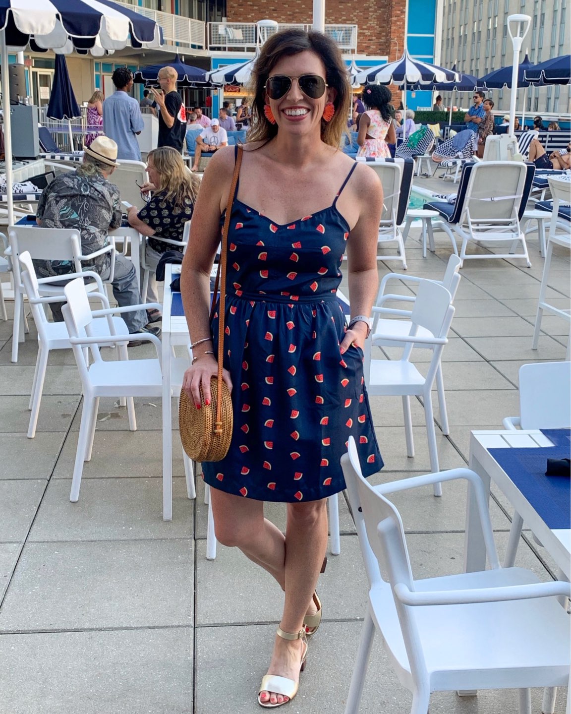 Welcome July + June Instagram Roundup - I'm Fixin' To - @mbg0112 | Welcome July + June Instagram Fashion Roundup by popular North Carolina life and style blog, I'm Fixin' To: image of a woman standing outside by a public pool wearing a J. Crew Factoru watermelon dress and holding a Novum Crafts Rattan Bags for Women.