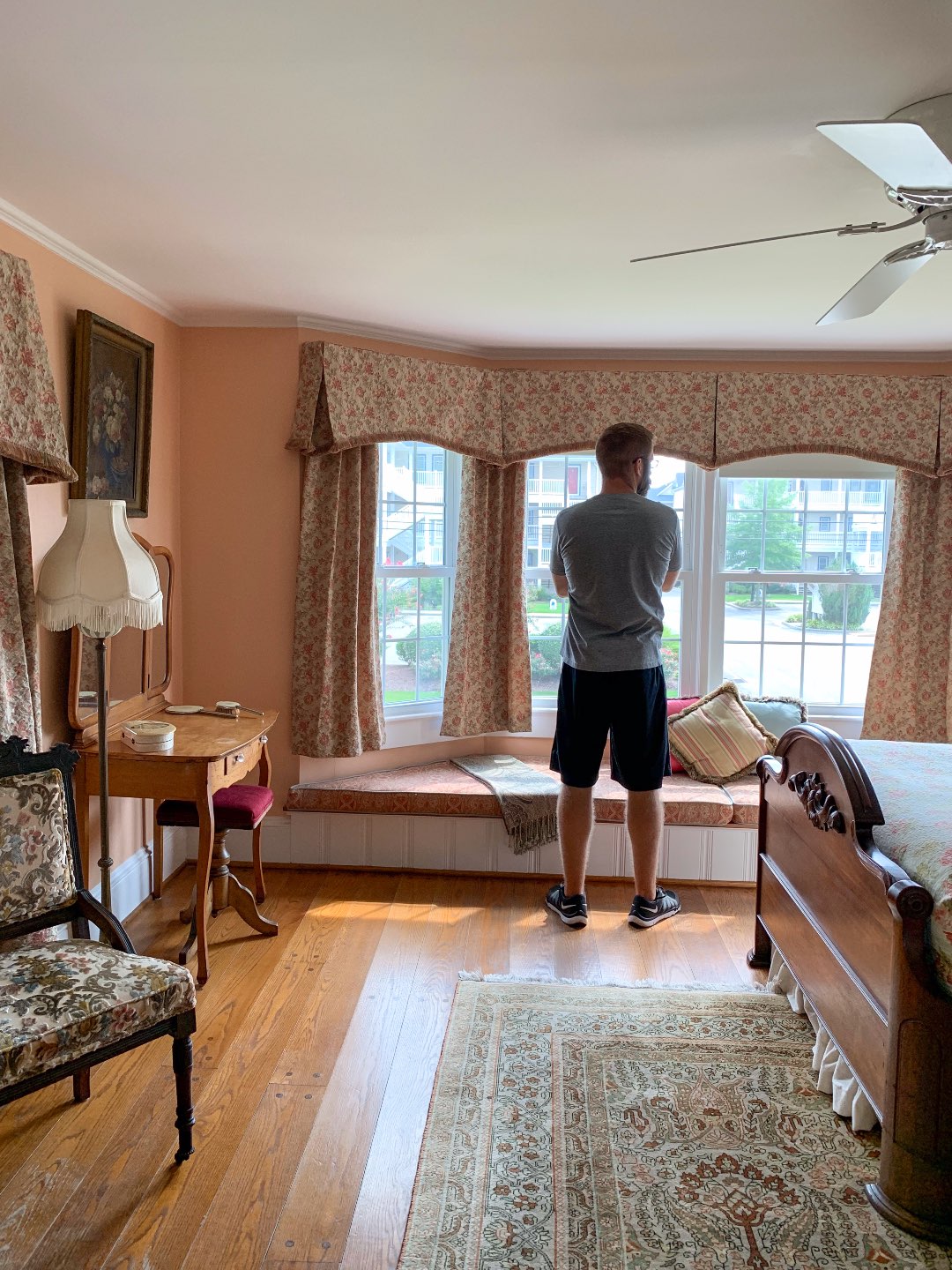 North Carolina Favorite: Between Water and Main Bed & Breakfast in Belhaven - I'm Fixin' To - @mbg0112 | North Carolina Favorite: Between Water and Main Bed & Breakfast in Belhaven by popular North Carolina Blogger, I'm Fixin' To: image of a man looking out a bedroom window at Between Water and Main Bed and Breakfast.