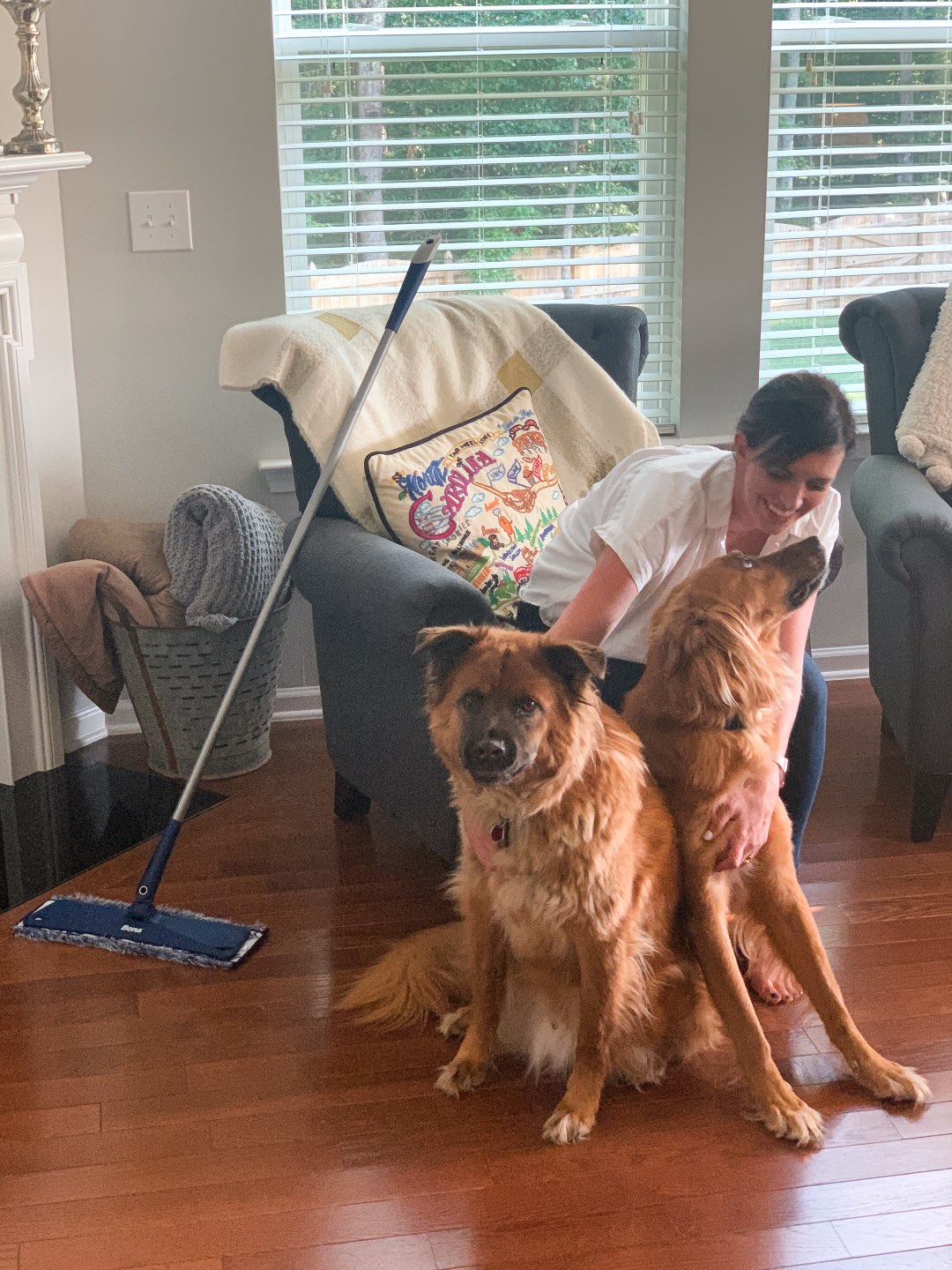 Keeping Our Floors Clean with Bona Essentials - I'm Fixin' To - @mbg0112 | Keeping Our Floors Clean with Bona Essentials by popular lifestyle blog, I'm Fixin' To: image of a woman sitting in an arm chair with her two large dogs at her feet and a Bona Essentials mop propped up against the chair.