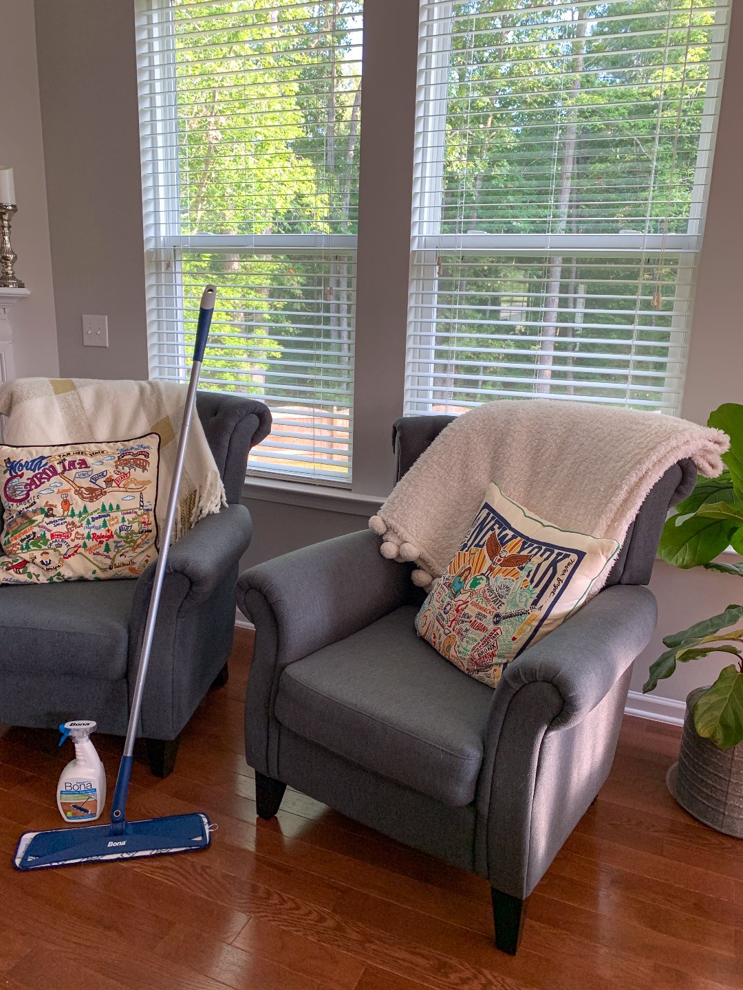 Keeping Our Floors Clean with Bona Essentials - I'm Fixin' To - @mbg0112 | Keeping Our Floors Clean with Bona Essentials by popular lifestyle blog, I'm Fixin' To: image of a bottle of Bona Essentials Hardwood Floor Deep Cleaner and a Bona essentials mop resting on a wood floor next to a grey armchair. 