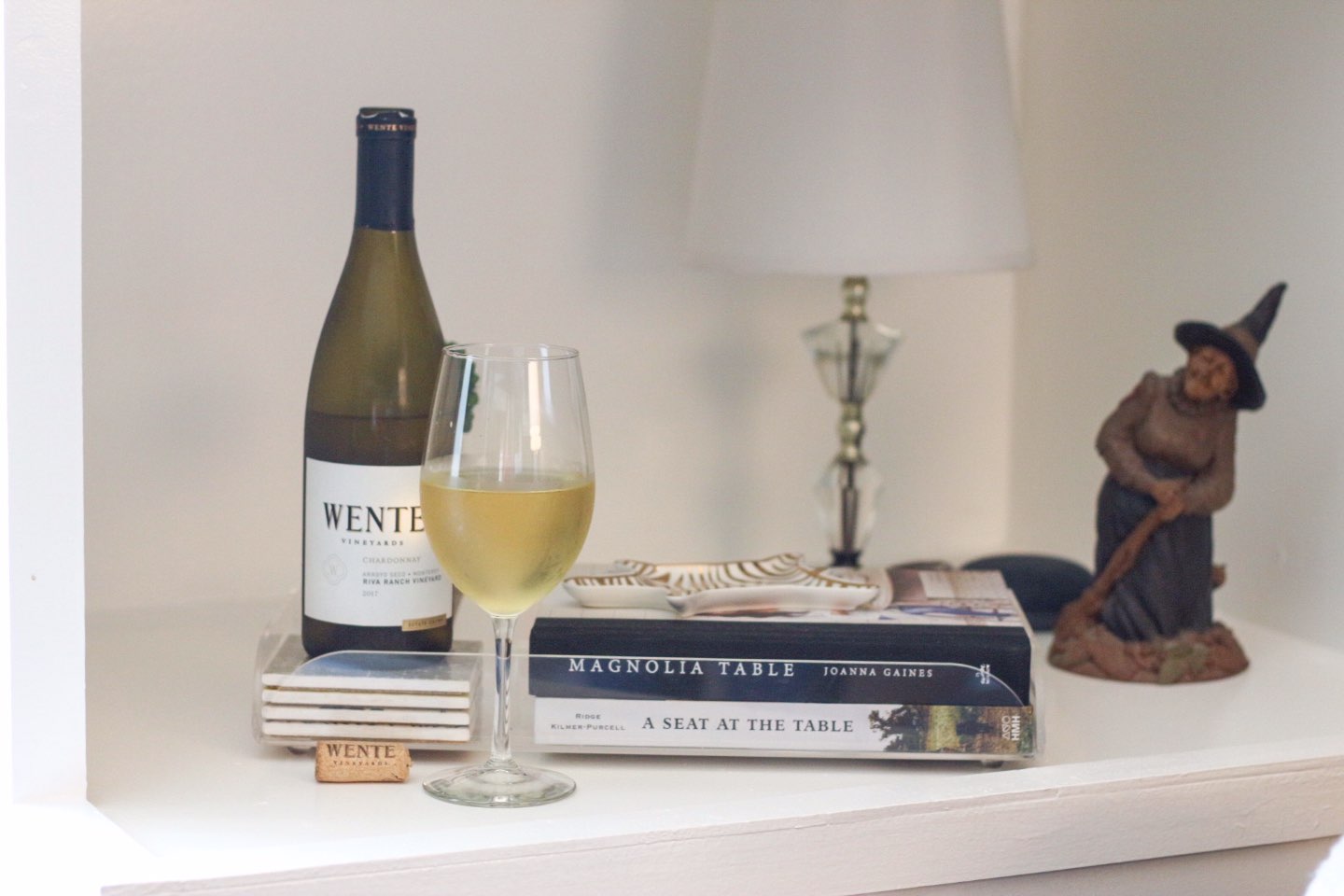 How I Make Time for Decorating with Wente Vineyards - I'm Fixin' To - @mbg0112 | How I Make Time for Decorating with Wente Vineyards by popular North Carolina lifestyle blog, I'm Fixin' To: image of a bottle and glass of Wente Vineyards wine on a book shelf next to a pile of books.