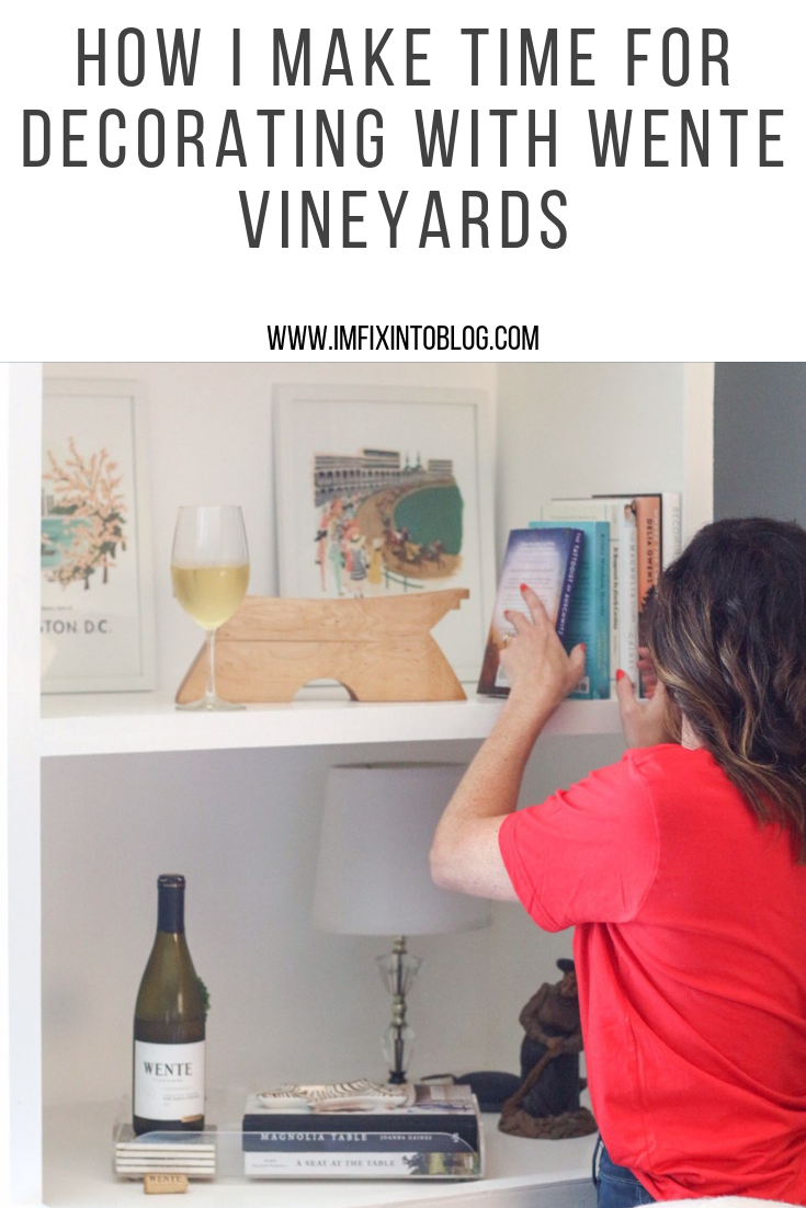 How I Make Time for Decorating with Wente Vineyards - I'm Fixin' To - @mbg0112 | How I Make Time for Decorating with Wente Vineyards by popular North Carolina lifestyle blog, I'm Fixin' To: Pinterest image of woman placing a book on her book shelf with a bottle and glass of Wente Vineyards wine on a book shelf next to a pile of books.