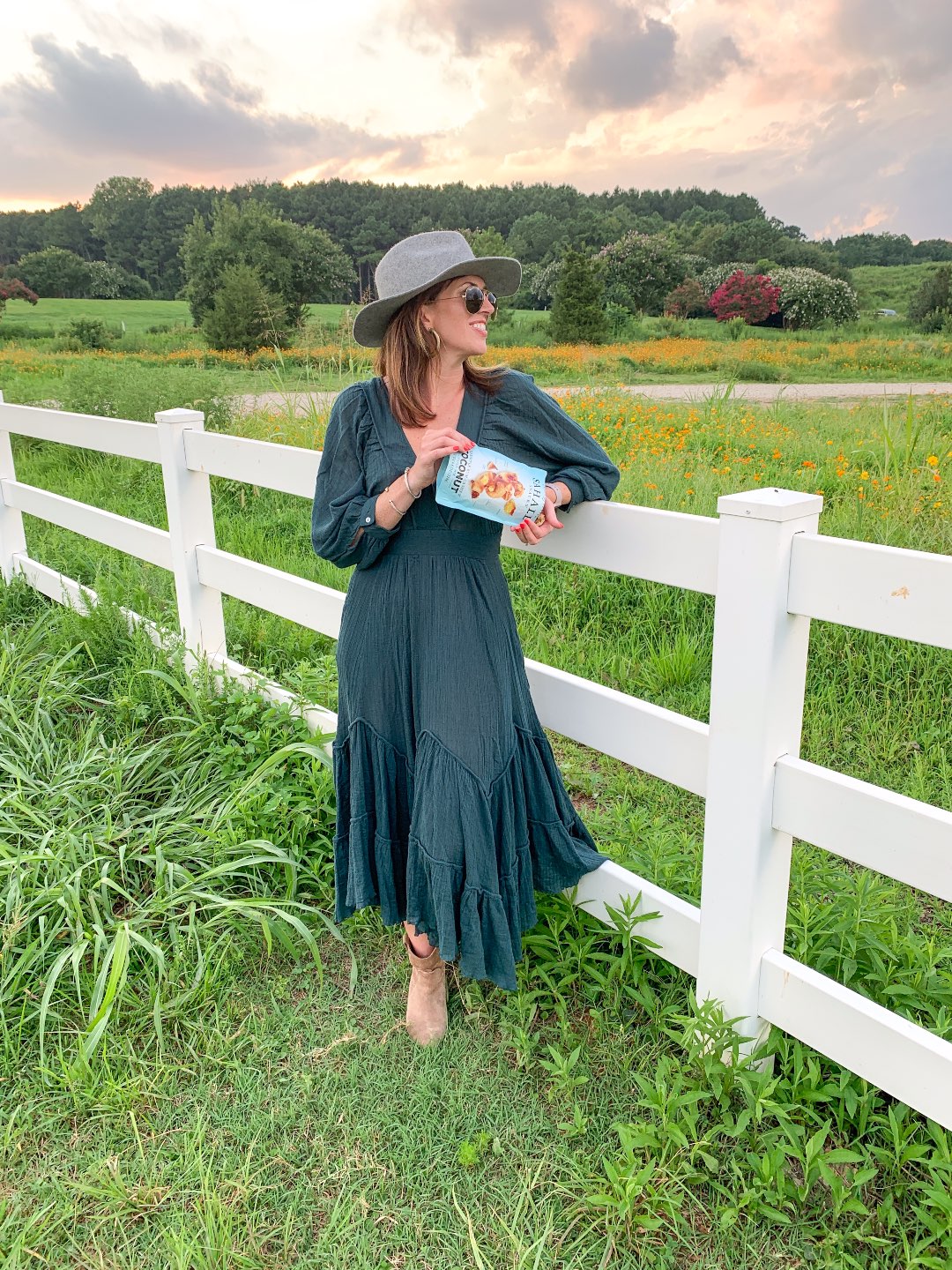 Quick Snack Ideas When You're On the Go by popular NC life and style blogger, I'm Fixin' To: image of a woman standing outside in a field and pouring a bag of Sahale Snacks coconut mix into her hands.