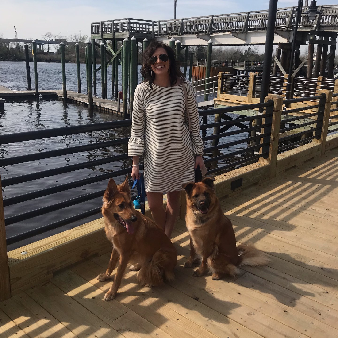 One Year Since Hurricane Florence in North Carolina and How to Help Ocracoke by popular North Carolina blog, I'm Fixin' To: image of a woman standing on a pier with her two dogs.
