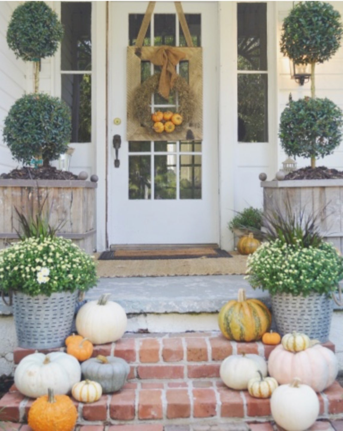 Inspiration Board: Fall Front Porch Ideas - I'm Fixin' To - @mbg0112 | Inspiration Board: Fall Front Porch Ideas by popular North Carolina life and style blog, I'm Fixin' To: image of a front porch decorated with potted white mums, pumpkins, and a fall wreath.