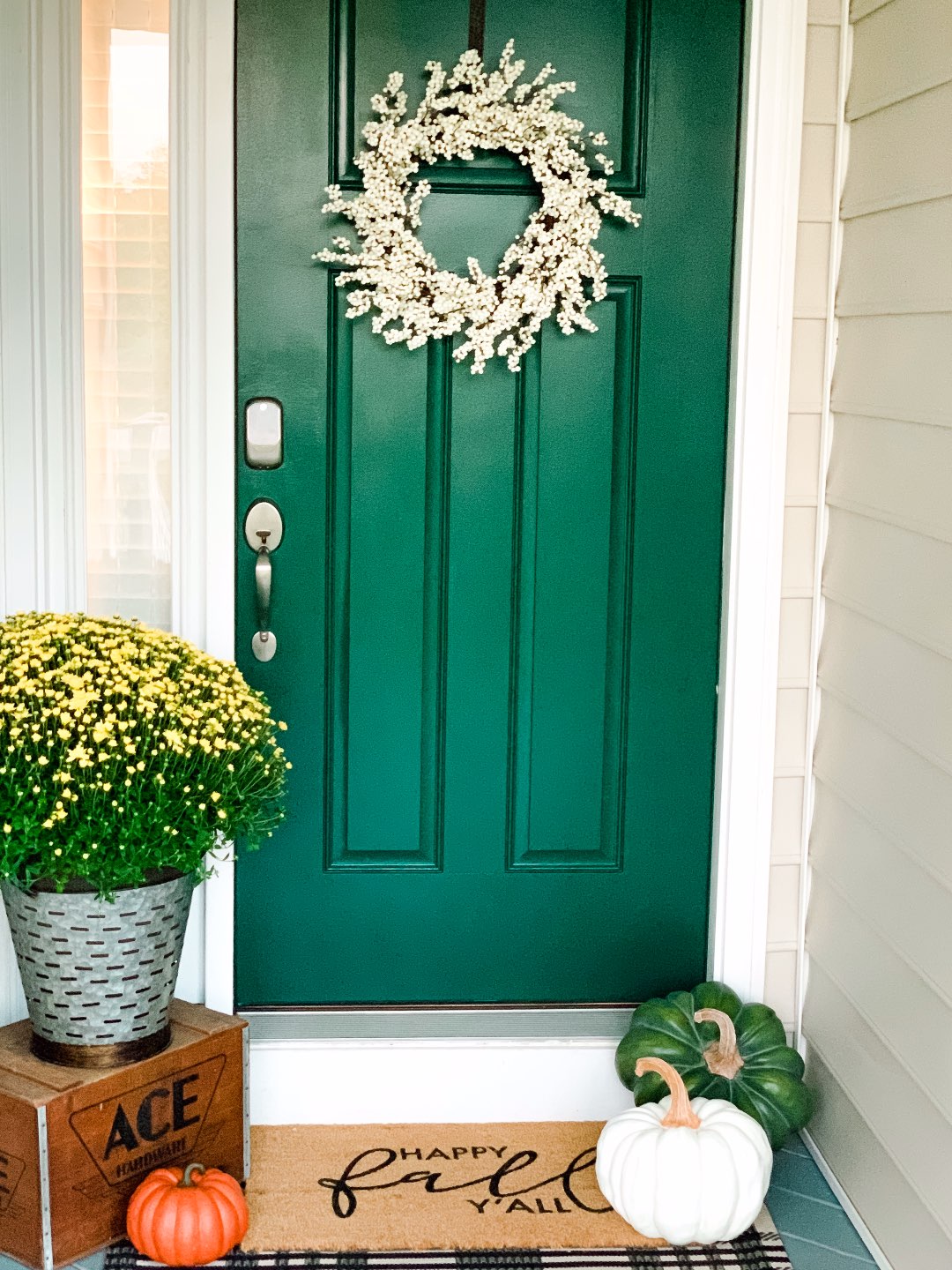 Inspiration Board: Fall Front Porch Ideas by popular North Carolina life and style blog, I'm Fixin' To: image of a front porch decorated with a white wreath, potted yellow mums, and pumpkins.