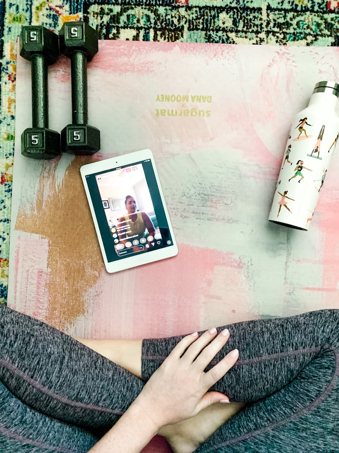 My Favorite Ways to Stay Active While Quarantined - I'm Fixin' To - @mbg0112 | How to Stay Active at Home by popular NC lifestyle blog, I'm Fixin' To: image of a woman sitting on a yoga mat that has a white metal water bottle, 5 lbs hand weights, and a ipad on it.