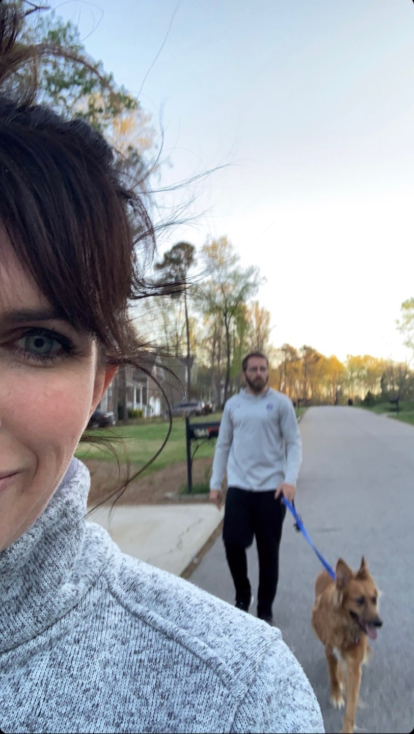 My Favorite Ways to Stay Active While Quarantined - I'm Fixin' To - @mbg0112 | How to Stay Active at Home by popular NC lifestyle blog, I'm Fixin' To: image of a woman and her husband walking their dog outside.