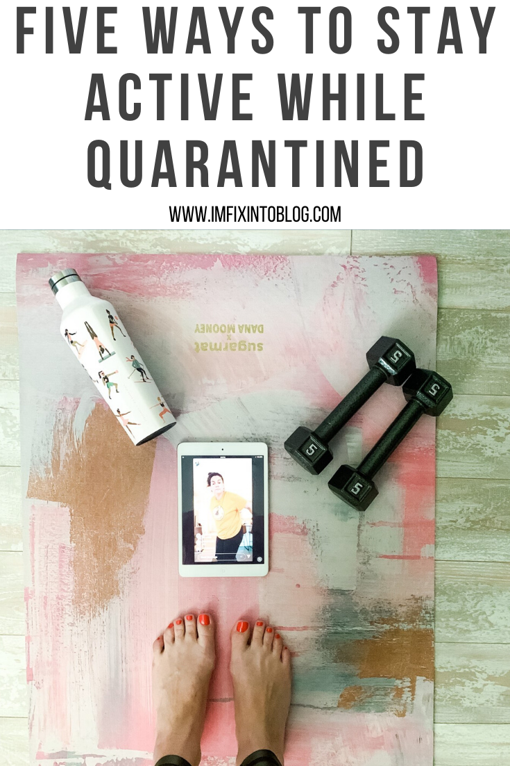 My Favorite Ways to Stay Active While Quarantined - I'm Fixin' To - @mbg0112 | How to Stay Active at Home by popular NC lifestyle blog, I'm Fixin' To: Pinterest image of a woman standing on a yoga mat that has a white metal water bottle, 5 lbs hand weights, and a ipad on it.