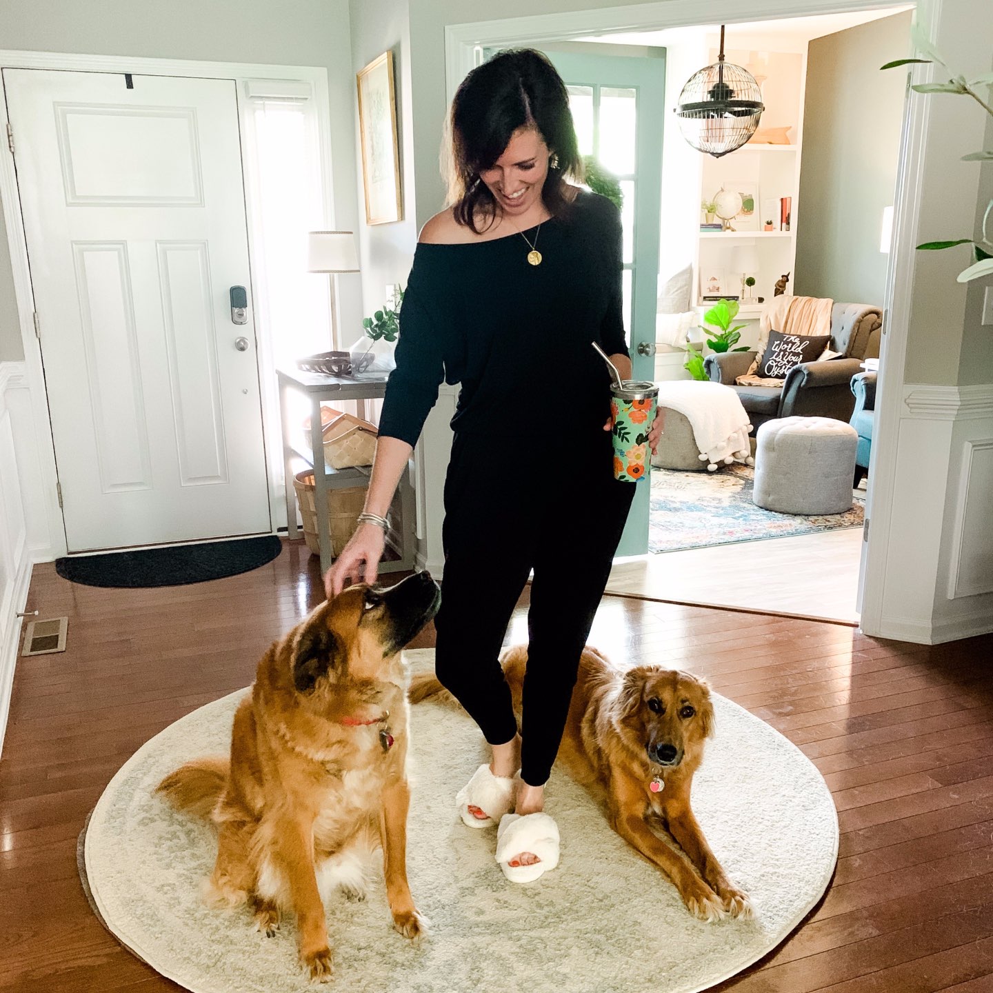 How I'm Learning to Do Nothing - I'm Fixin' To - @mbg0112 | Learning to do Nothing by popular N.C. lifestyle blog, I'm Fixin' To: image of a woman wearing a black jumper and white fuzzy slippers while she stand next to her two dogs in the entryway of her home. 