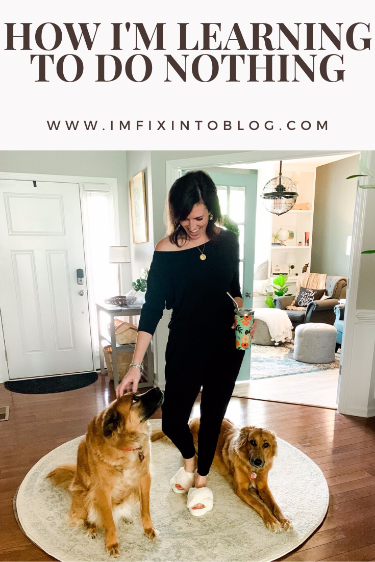 How I'm Learning to Do Nothing - I'm Fixin' To - @mbg0112 |  Learning to do Nothing by popular N.C. lifestyle blog, I'm Fixin' To: image of a woman wearing a black jumper and white fuzzy slippers while she stand next to her two dogs in the entryway of her home. 