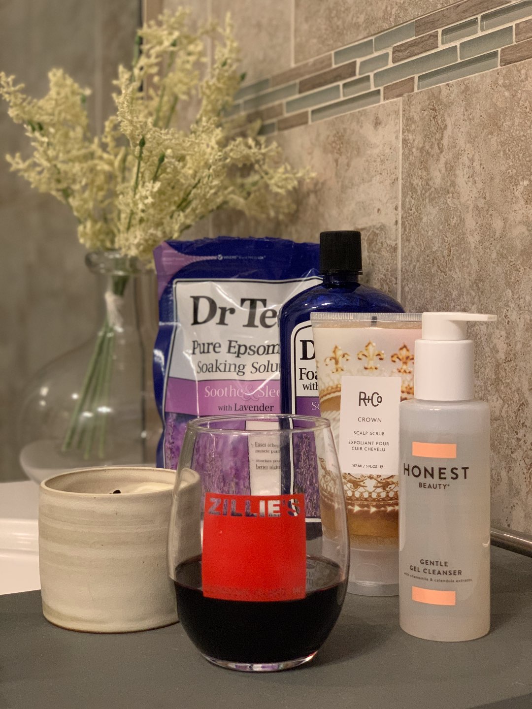 Home Fragrances for an Instant Pick-Me-Up during Quarantine (or Anytime!) - I'm Fixin' To - @mbg0112 | Home Fragrances by popular N.C. life and style blog, I'm Fixin' To: image of a bag of Dr. Teal lavender epsome soaking solution, glass of wine, candle, and Honest Beauty Gentle Gel Cleanser on the edge of a bath tub.