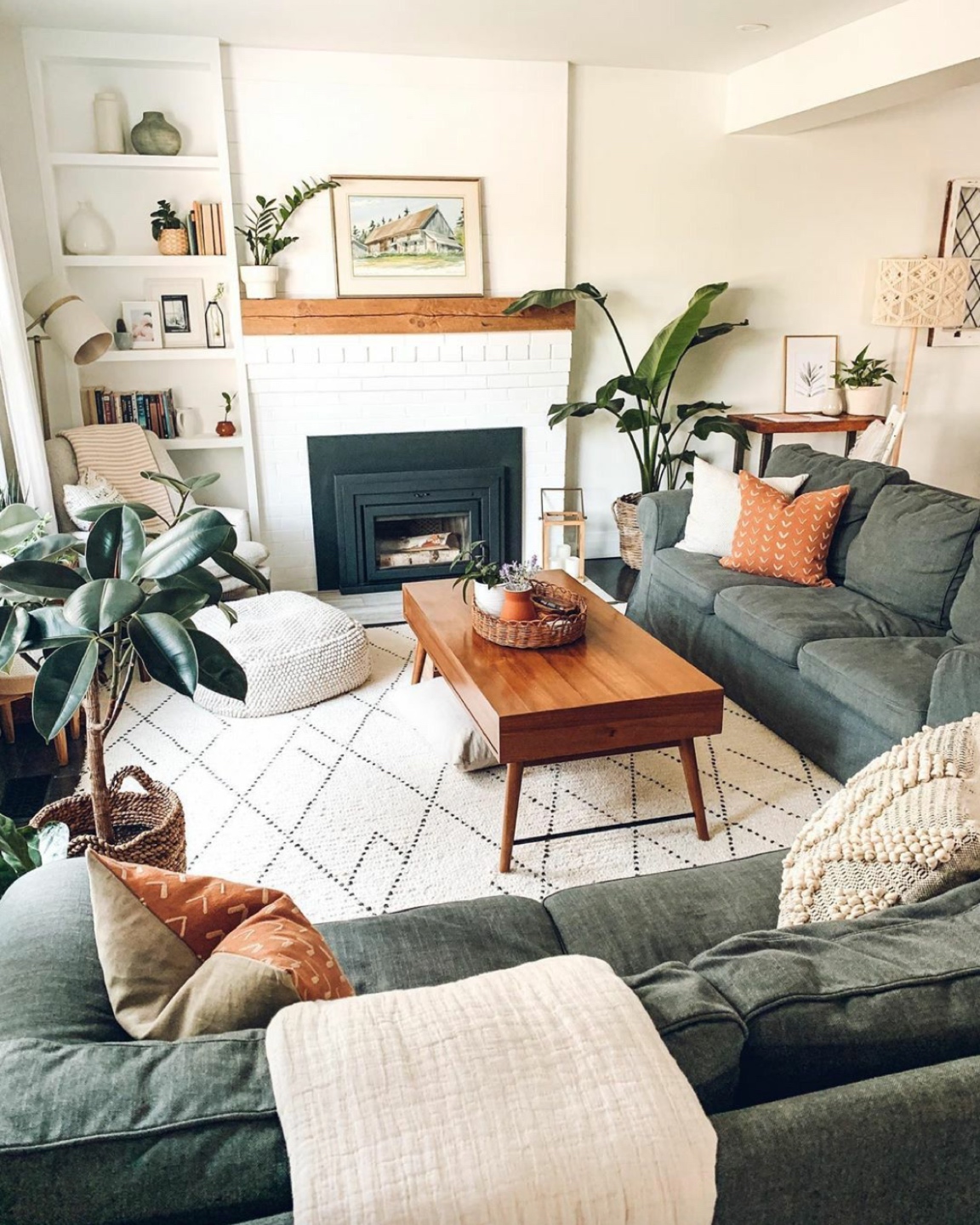 Inspiration Board: Living Room - I'm Fixin' To - @mbg0112 | Living Room Inspiration by popular N.C. life and style blog, I'm Fixin' To: image of a living room with a grey sectional couch, white fire place, black and white area rug, indoor plants, and a brown coffee table. 