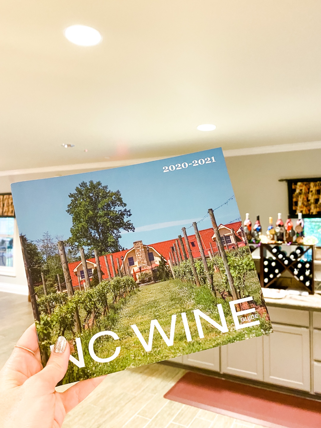 Western NC Wineries: 6 Wineries to Visit During your Next Girls' Weekend - I'm Fixin' To - @mbg0112 |Western NC Wineries by popular NC blog, I'm Fixin' To: image of a woman holding a NC wine guide at Adagio Vineyards. 