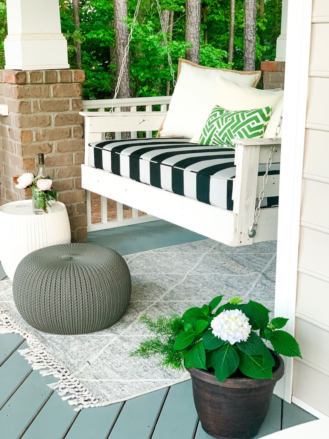 3 Years in Our Ranch: Home Updates - I'm Fixin' To - @imfixintoblog |Home Updates by popular NC life and style blog, I'm Fixin' To: image of a front porch decorated with a white porch swing, grey and white rug, potted plant, and grey ottoman.