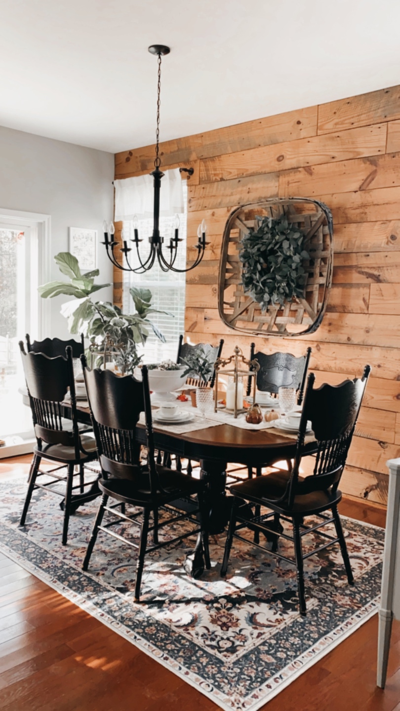 How to Make your Home Cozy: 10 Easy Ways - I'm Fixin' To - @imfixintoblog |How to Make Your Home Cozy by popular NC life and style blog, I'm Fixin' To: image of a black dining table with black chairs on a floral print area rug in front of a wood shiplap wall with a black chandelier hanging over it. 