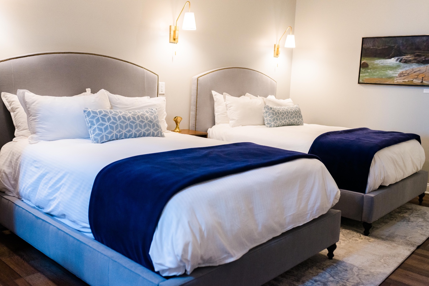 Places to Stay: The Colonial Inn in Hillsborough NC - I'm Fixin' To - @imfixintoblog |The Colonial Inn Hillsborough NC by popular NC travel blog, I'm Fixin' To: image of two twin size beds with grey fabric covered head boards, white bedding, blue and white lumbar pillows and blue throw blankets.