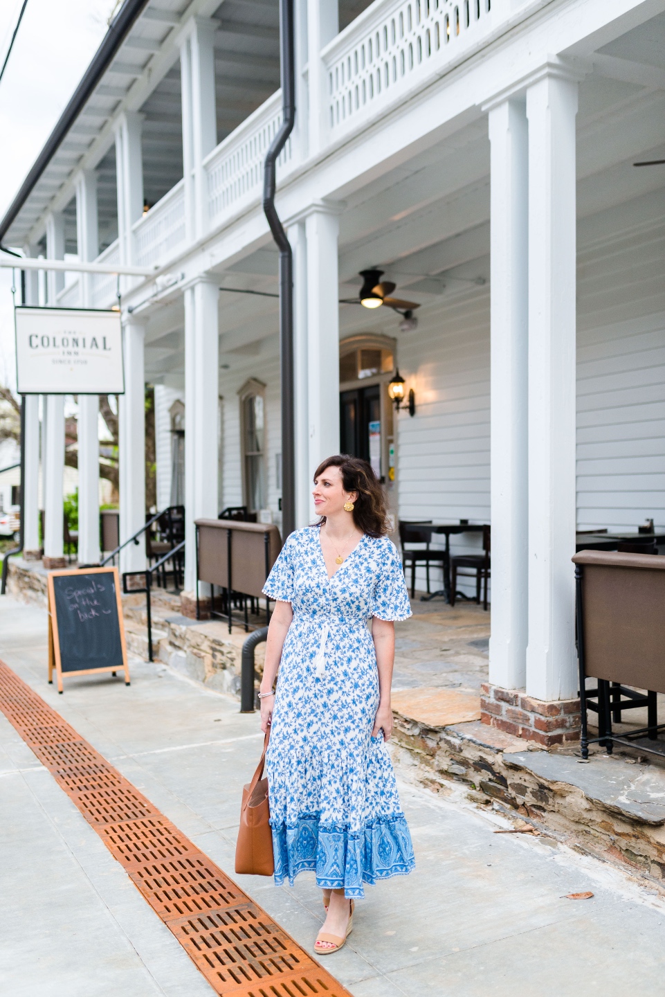 Places to Stay: The Colonial Inn in Hillsborough NC |The Colonial Inn Hillsborough NC by popular NC travel blog, I'm Fixin' To: image of a woman wearing a blue floral print maxi dress and standing outside of the Colonia Inn.