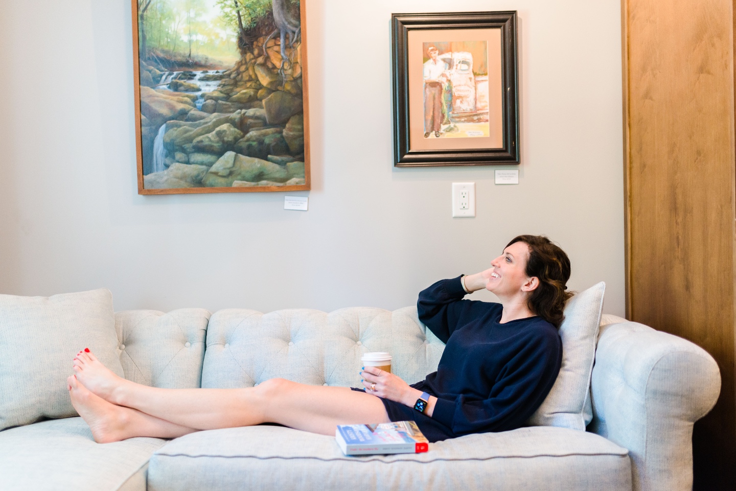 Places to Stay: The Colonial Inn in Hillsborough NC - I'm Fixin' To - @imfixintoblog |The Colonial Inn Hillsborough NC by popular NC travel blog, I'm Fixin' To: image of a woman sitting on a grey tuft sectional couch with cup of coffee and a book.