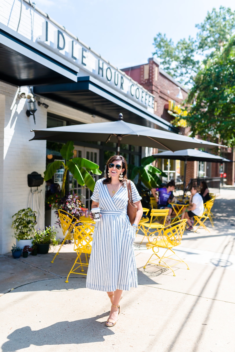 Social Media Free Sunday by popular NC lifestyle blog, I'm Fixin' To: image of a woman walking outside by some yellow tables and chairs and wearing a white and blue stripe dress.