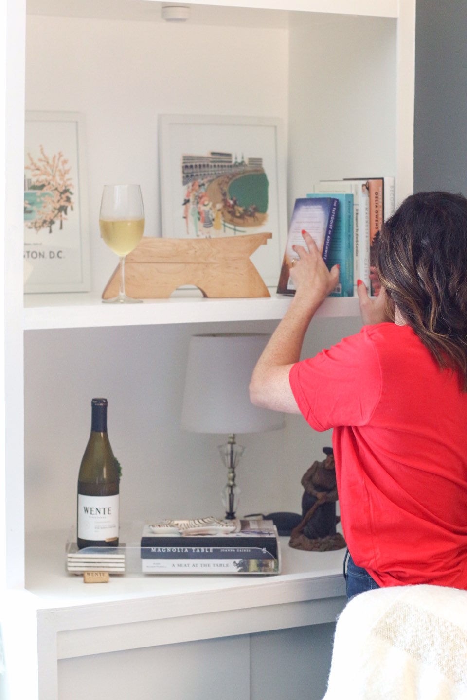 5 Affordable Ways to Keep your Home Feeling Fresh - I'm Fixin' To - @imfixintoblog | Ways to Refresh Your Home by popular NC life and style blog, I'm Fixin' To: image of a woman placing some books on a white bookshelf. 