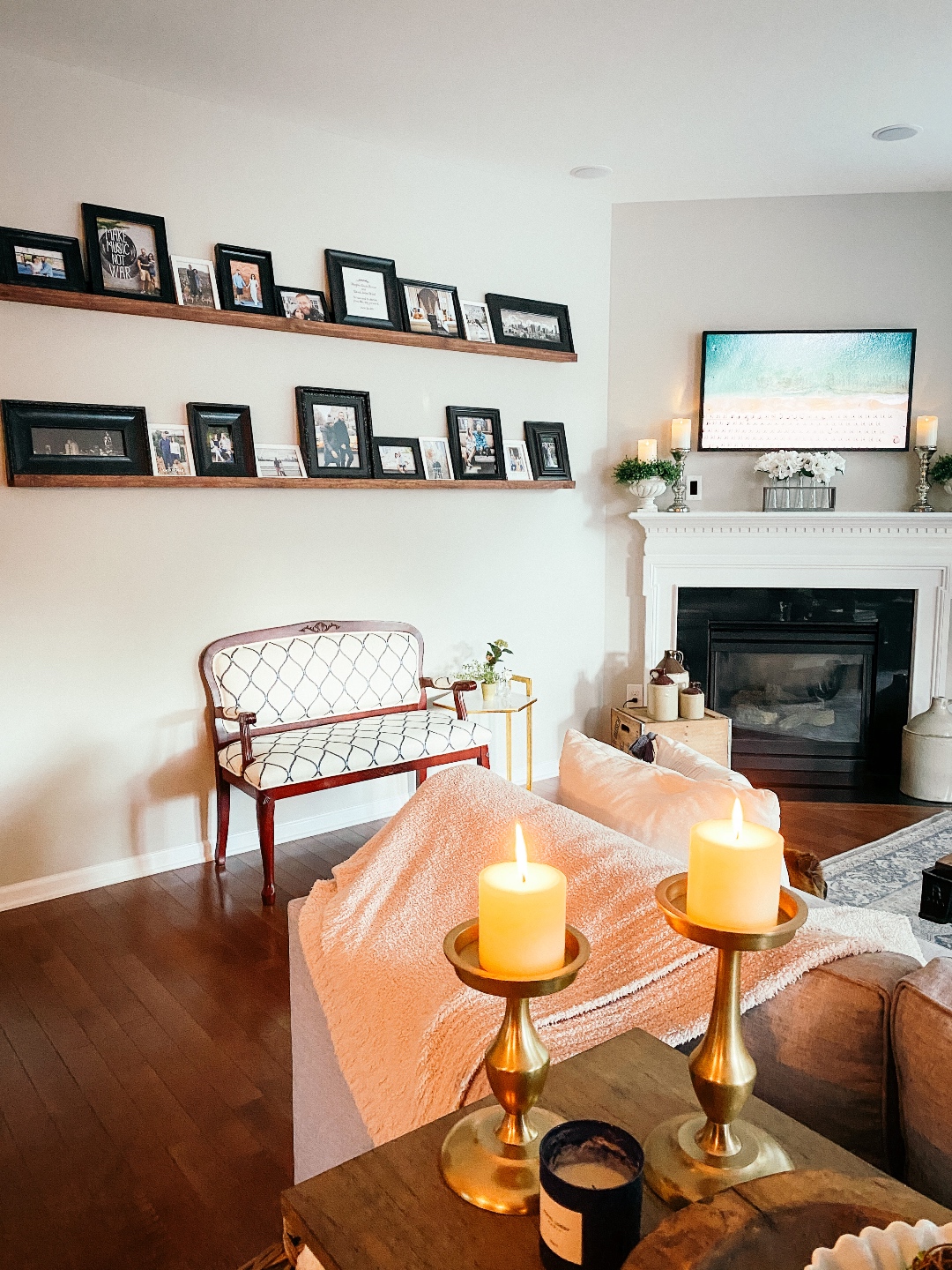Room Reveal: Blue and Gray Living Room Ideas - I'm Fixin' To - @imfixintoblog | Blue and Grey Living Room Ideas by popular NC life and style blog, I'm Fixin' To: image of a living room decorated with a blue and white rug runner, light wood sofa table, house plants, floating wood shelves with black picture frames, white pillar candles, wooden picnic basket, blue and white floral wallpaper, and grey sectional couch. 