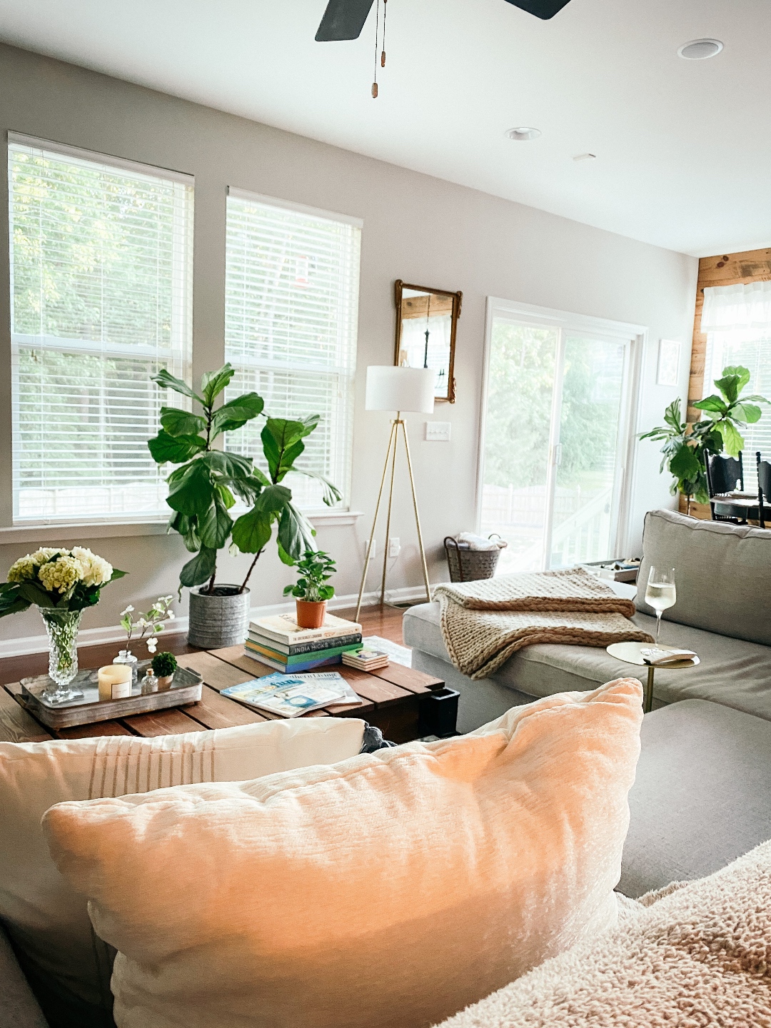 Room Reveal: Blue and Gray Living Room Ideas - I'm Fixin' To - @imfixintoblog | Blue and Grey Living Room Ideas by popular NC life and style blog, I'm Fixin' To: image of a living room decorated with a grey sectional couch, potted house plants, tripod floor lamp, and industrial wooden pallet coffee table. 