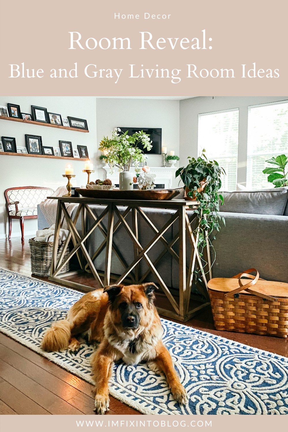 Room Reveal: Blue and Gray Living Room Ideas - I'm Fixin' To - @imfixintoblog | Blue and Grey Living Room Ideas by popular NC life and style blog, I'm Fixin' To: Pinterest image of a living room decorated with a blue and white rug runner, light wood sofa table, house plants, floating wood shelves with black picture frames, white pillar candles, wooden picnic basket, blue and white floral wallpaper, and cream cable knit throw blanket. 