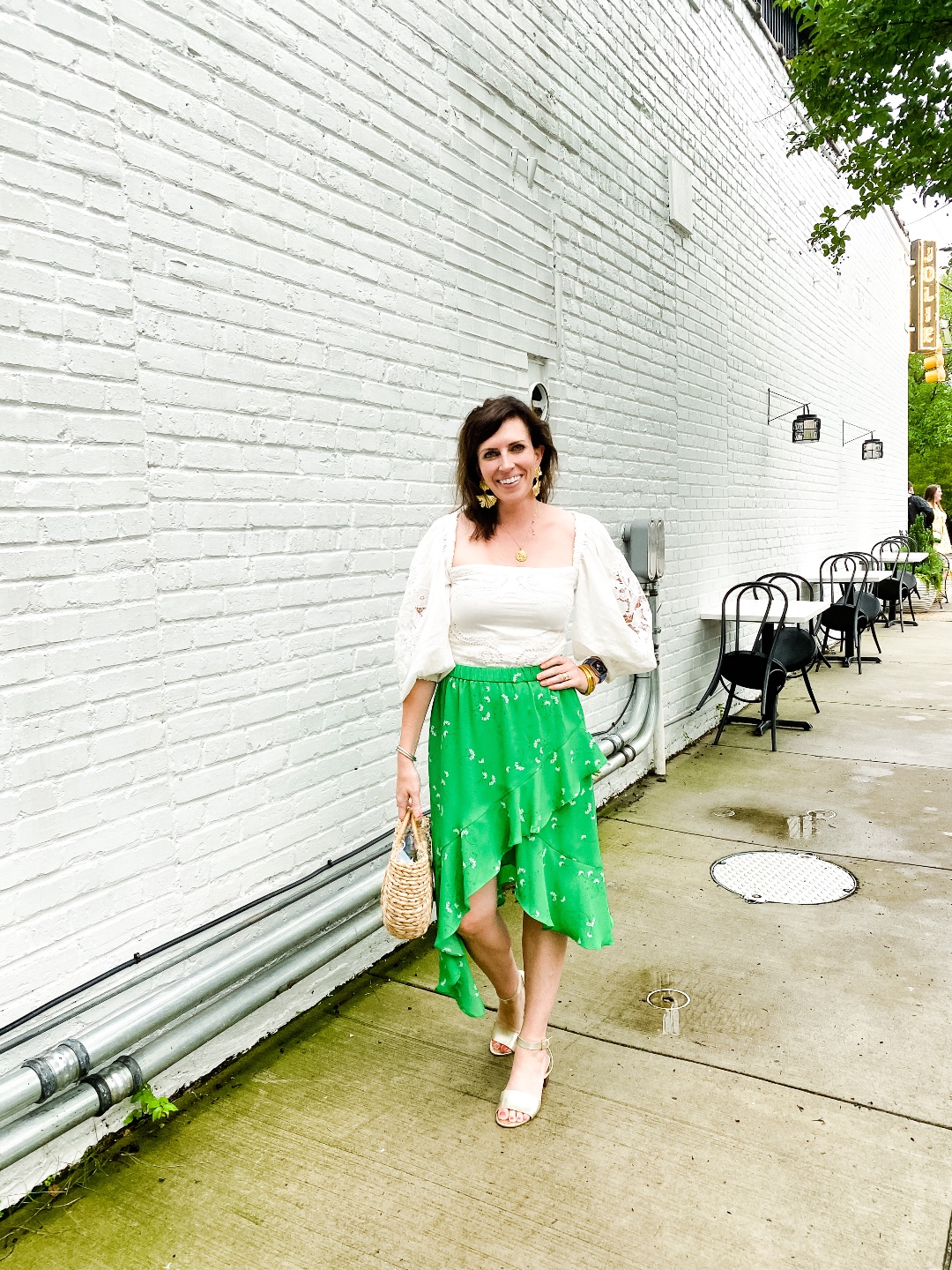 Style Diary: What I've Been Wearing this Spring - I'm Fixin' To - @imfixintoblog | Spring Essentials by popular NC fashion blog, I'm Fixin' To: image of a woman standing next to a white brick building and wearing a cream puff sleeve blouse and green ruffle a-line skirt.