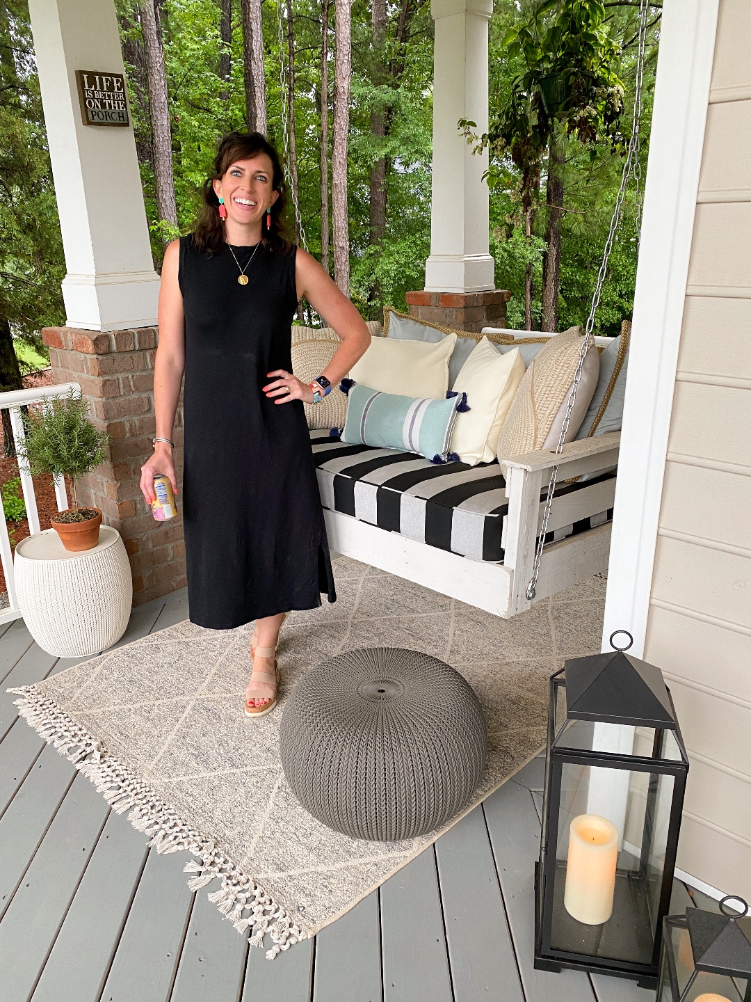 Style Diary: What I've Been Wearing this Spring - I'm Fixin' To - @imfixintoblog | Spring Essentials by popular NC fashion blog, I'm Fixin' To: image of a woman standing on a porch next to a wooden porch swing with a black and white stripe cushion and wearing a black sleeveless maxi dress and colorful statement earrings.