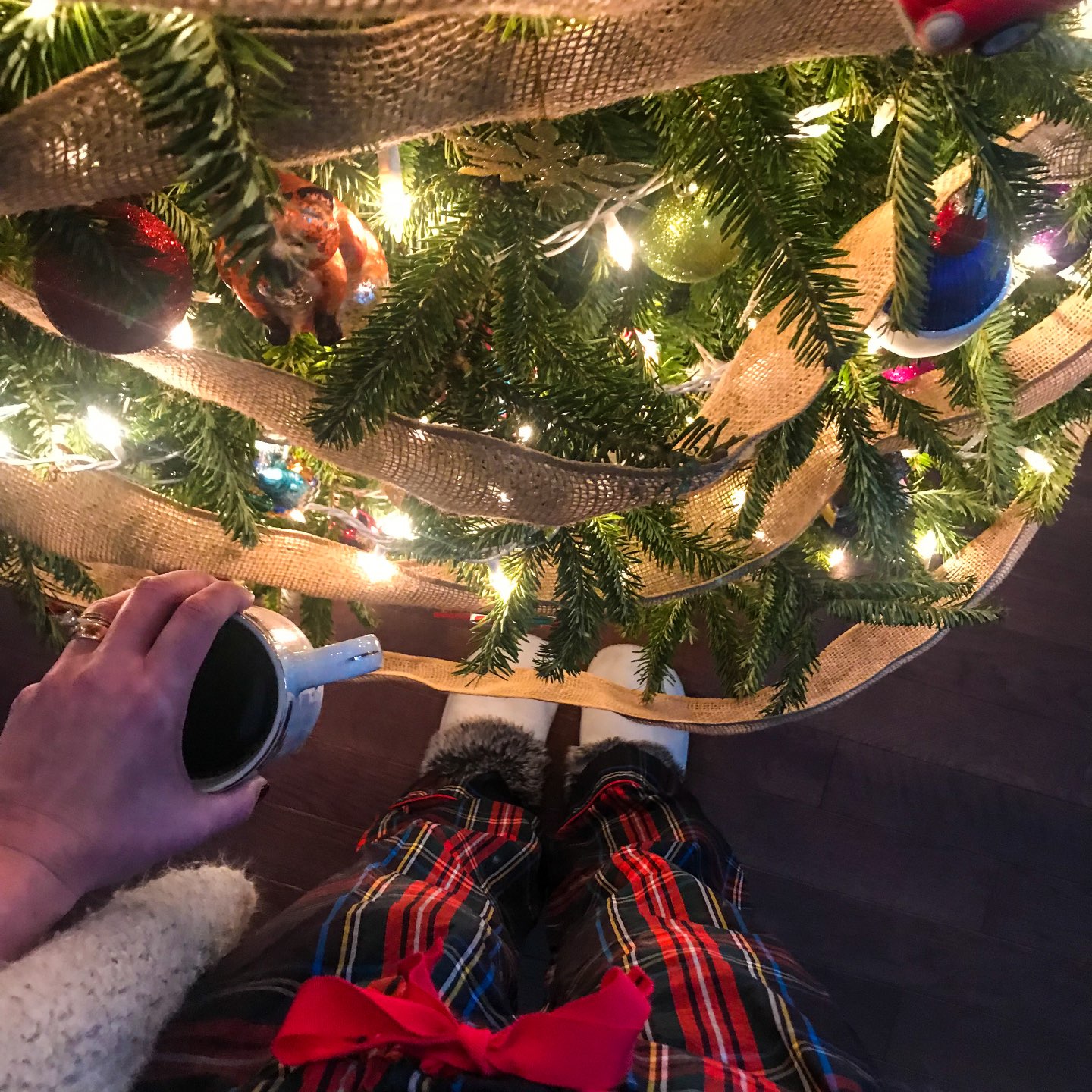 woman holding a mug and standing near the christmas tree and sharing her Holiday Shop list woman holding a mug and standing near the christmas tree and sharing her Holiday Shop list